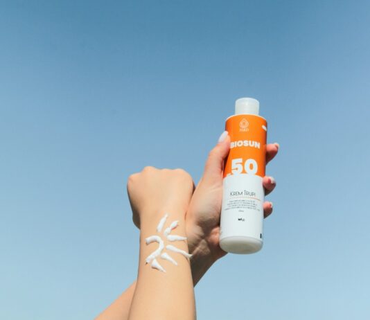 여름철, 피부를 건강하게 유지하는 5가지 방법 a person holding a bottle of sunscreen in their hand