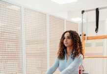 필라테스, 몸과 마음을 동시에 건강하게 하는 비결 a woman in a gray top and leggings is on a rowing machine