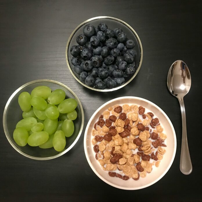 a bowl of cereal, a bowl of grapes and a bowl of cereal