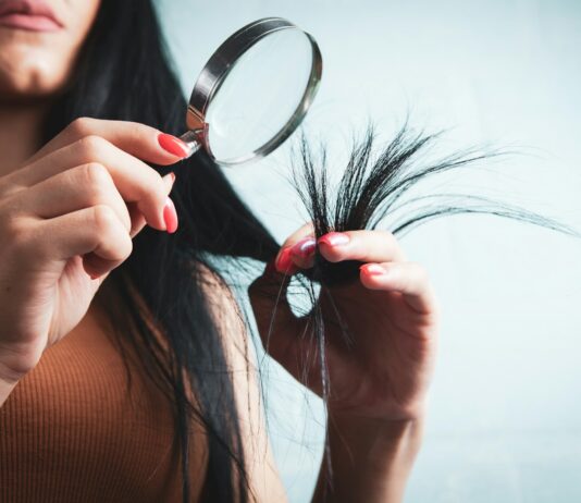 건강한 모발을 위한 똑똑한 헤어 관리, 일상 속 실천법은? Woman examining split ends of hair with magnifying glass