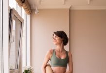집과 직장에서 더 가까워진 필라테스, 건강한 일상을 만드는 실천법 a woman in a green sports bra top and leggings holding a yoga mat