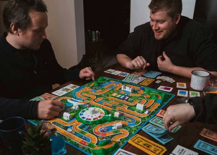 Photo by 2H Media two men playing a game of monopoly on a table
