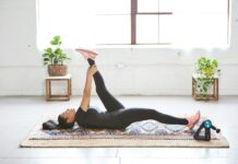 웰니스 회복, 현대인의 필수 건강 전략으로 떠오르다 woman in black tank top and black leggings lying on black and white floral area rug